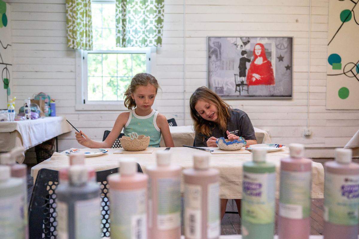Campers Cami Gibbs, left, and Emily Lemasson paint glaze onto their bowls during the Summer Youth Camp at the Cain Center for the Arts in Cornelius, NC, Thursday June 26, 2025.