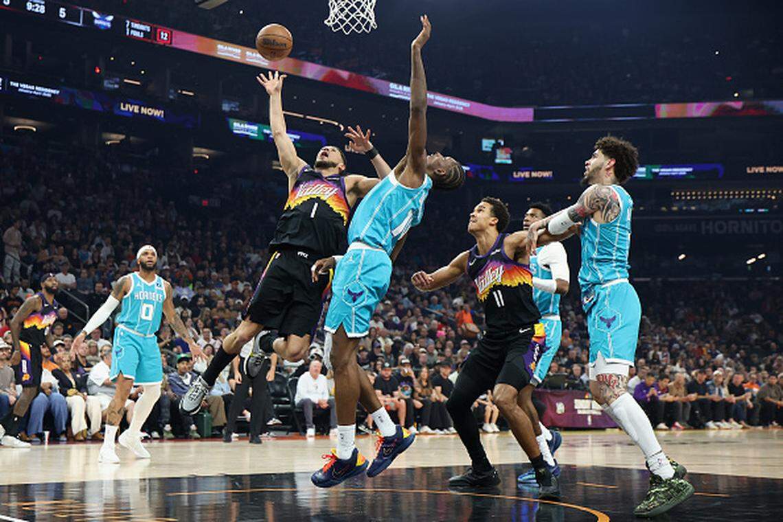 Devin Booker of the Phoenix Suns attempts a shot against Moussa Diabate of the Charlotte Hornets during the first half of the NBA game at Mortgage Matchup Center.