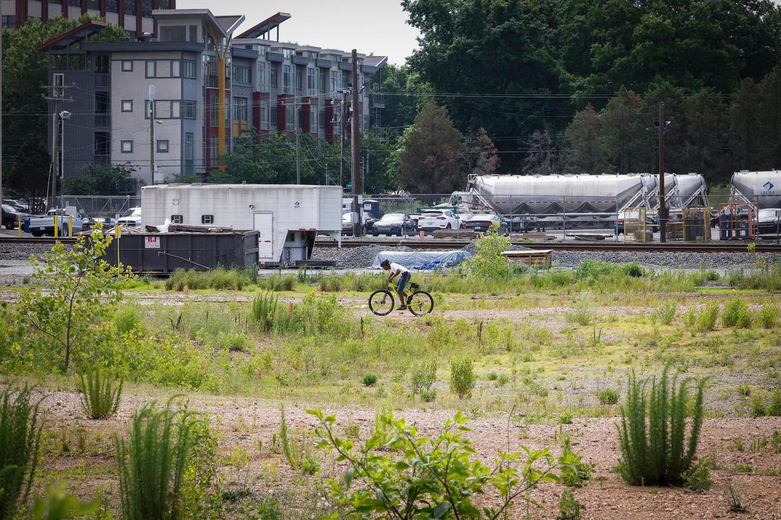 A man rides a bike nearby a century-old mill that has been producing flour in Charlotte for the past 30 years. A rezoning petition has led to concerns about how to create more housing types near industrial sites.