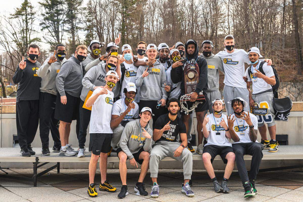 Appalachian State basketball players and coaches pose on campus after returning from the Sun Belt conference tournament with a trophy and their first NCAA tournament berth since 2000.