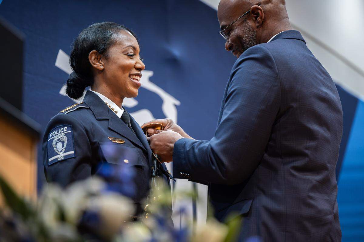 Chief Estella Patterson's husband, Lance, right, pins her badge on during her during her swearing in ceremony at the Charlotte Police and Fire Training Academy in Charlotte, N.C., on Friday, December 5, 2025.