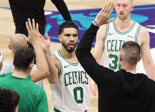 Boston Celtics forward Jayson Tatum, center, is congratulated by his teammates after hitting a 3-point basket against the Charlotte Hornets Sunday. Tatum had a game-high 32 points in the Celtics’ 15-point win.