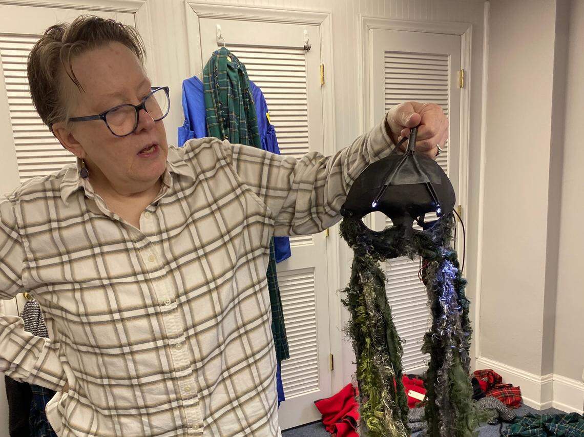 Opera Carolina costume coordinator Betsy Blackmore holds up a mask adorned with tiny lights and dangling fringe that will be worn by one of the witches in the opera’s upcoming performances of Macbeth.