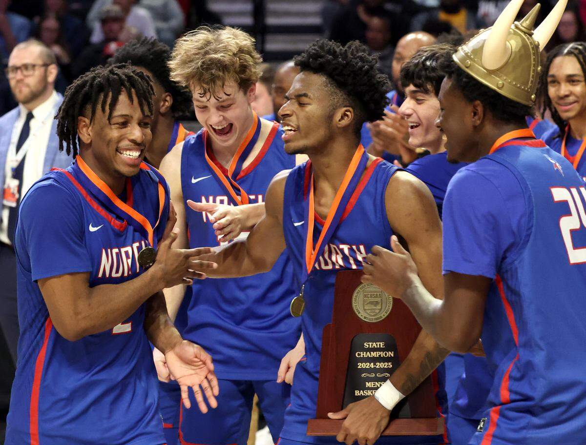 North Meck Vikings Carson Evans, left, is congratulated by his teammates after being named the MVP following the team’s game against New Hanover in the boys NCHSAA 4A State Championship game at Lawrence Joel Veterans Coliseum in Winston-Salem, NC on Saturday, March 15, 2025. North Meck defeated New Hanover 59-56.
