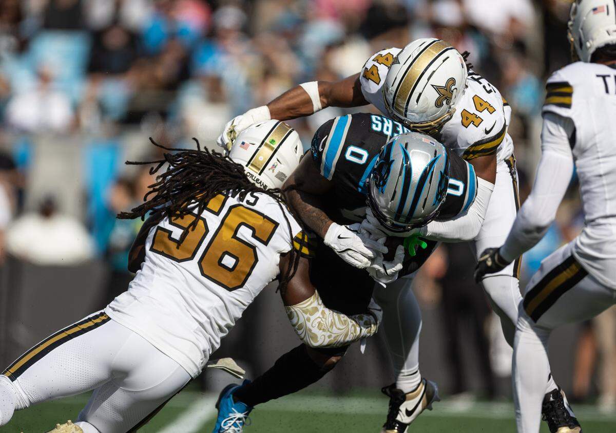 Carolina Panthers tight end Ja'Tavion Sanders (center) is taken down by two New Orleans Saints in the Panthers’ 17-7 home loss to the Saints on Nov. 9, 2025.