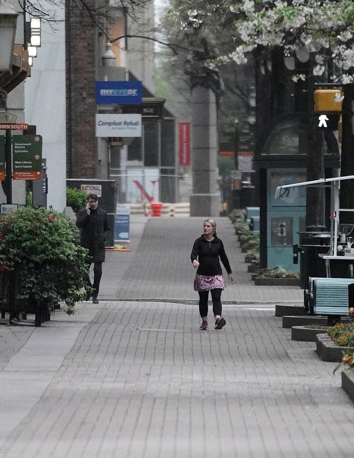 A pedestrian walks along a deserted sidewalk along Tryon Street in uptown Charlotte Tuesday morning, March 24, 2020.
