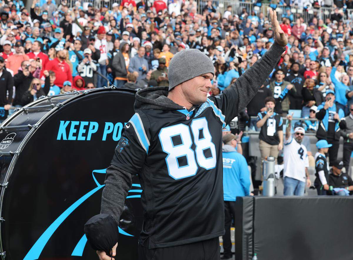 Former Carolina Panthers tight end Greg Olsen waves to the crowd after banging the drum on Dec. 21, 2025, at Bank of America Stadium.