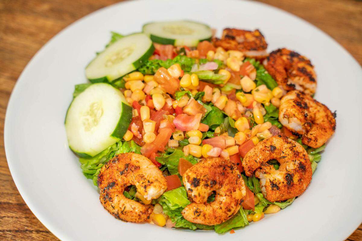 A salad with blackened shrimp at Providence Road Sundries has romaine, cucumbers, corn salsa and tomatoes.