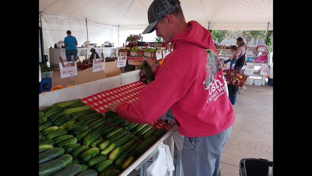 Garrett Deweese, brother-in-law of Josh’s Farmers Market owner Josh Graham, arranges cucumbers before the opening of the new location of the market on River Highway in Mooresville, NC, on Friday, Sept. 29, 2023.