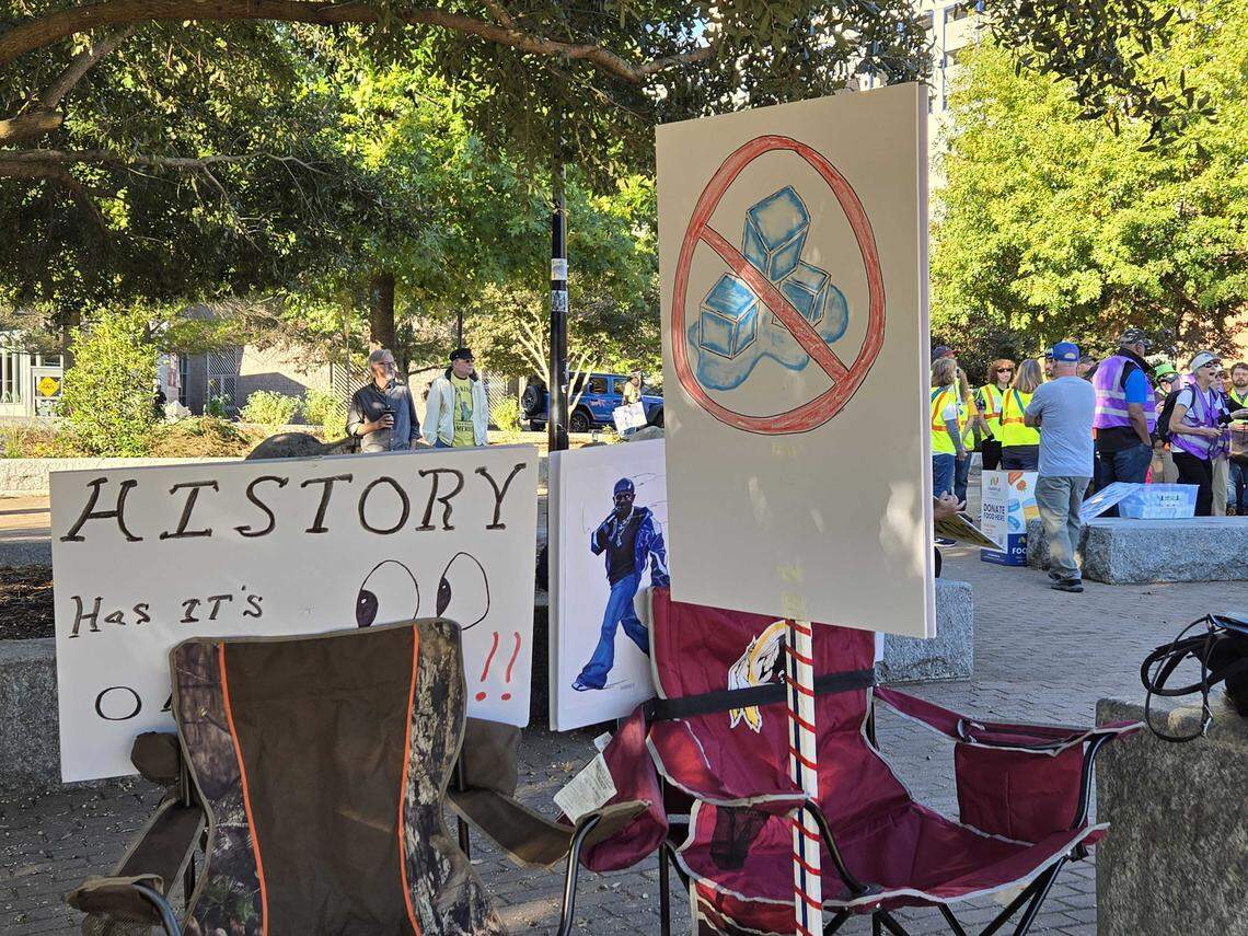 Various signs are lined up for the ‘No Kings’ protest in uptown Charlotte on Saturday, Oct. 18. Protesters began to arrive in the park for the rally and march around 9 a.m.