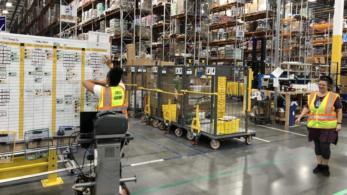 An associate at the Amazon fulfillment center in Kannapolis, Seneman Pollock, organizes magnets on a board that tells employees in the outbound section what station to work at.