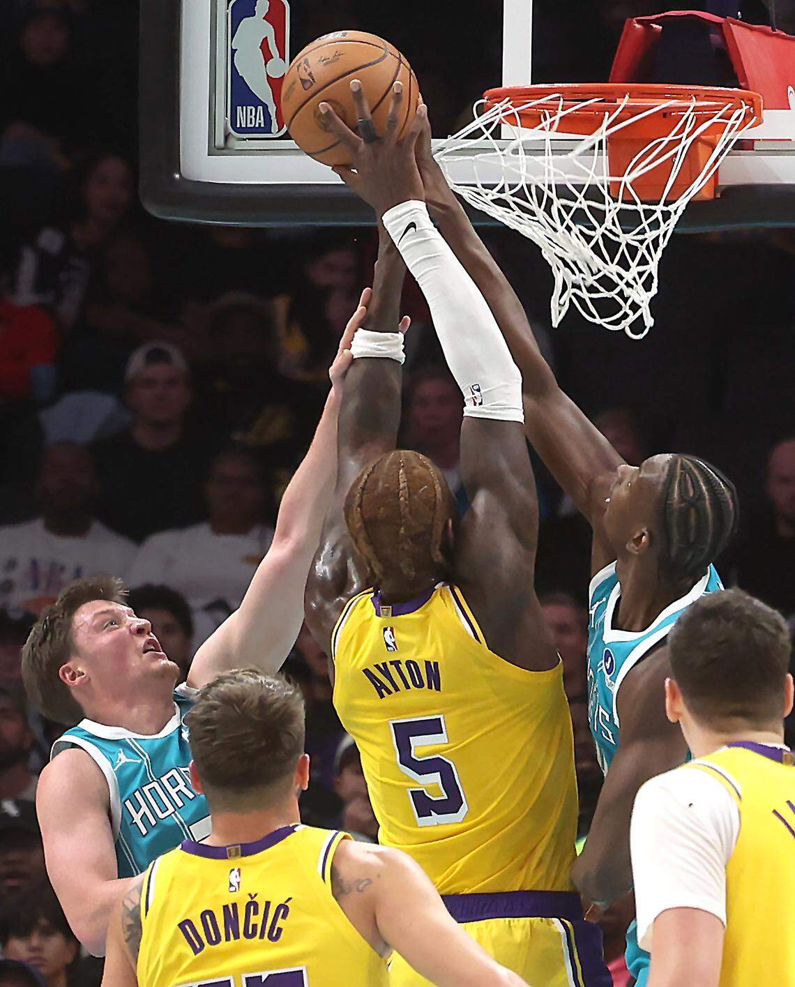 Charlotte Hornets forward/center Moussa Diabate, right, blocks a shot by Los Angeles Lakers center Deandre Ayton, center, during action on Monday at Spectrum Center. Assisting at left is Hornets guard/forward Kon Knueppel.