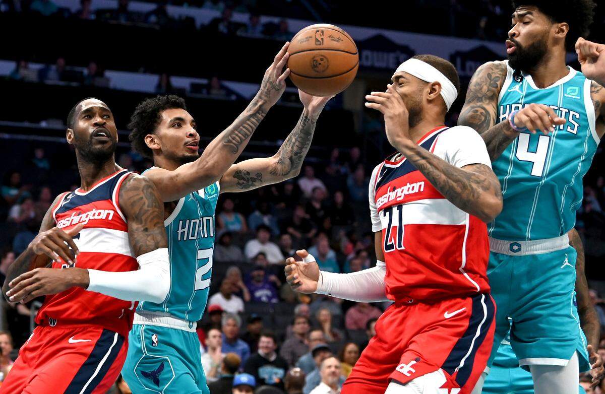 Charlotte Hornets guard James Bouknight, center, grabs ahold of a rebound between Washington Wizards guard Will Barton, left and forwward/center Daniel Gafford, right, during first half action on Monday, November 7, 2022 at Spectrum Center in Charlotte, NC.