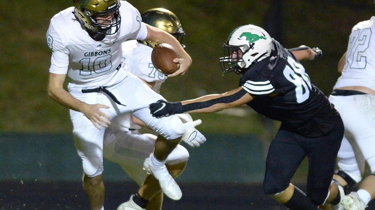 Myers Park defensive end Deems May, right, reaches out to grab ahold of Cardinal Gibbons quarterback Connor Clark, left, during fourth quarter action at Myers Park High School on Friday, September 24, 2021. May made the sack with defensive tackle Jordan Tinsley. The Mustangs defeated Cardinal Gibbons in overtime on a field goal, winning 16-13.