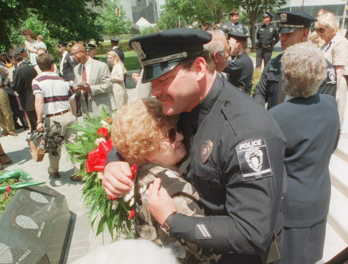 Lila Griffin, mother of slain Charlotte Police officer Eugene Griffin gets a hug from Officer D. J. Offnick at the Police Memorial near the Law Enforcement Center.