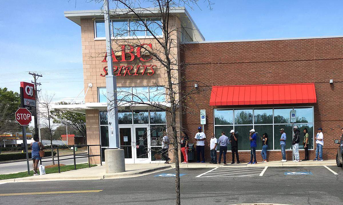 As clerks inside ABC Store #5 filled their orders and took their payments customers lined up outside at 2915 Wilkinson Blvd on Friday, Mar.20, 2020. 
