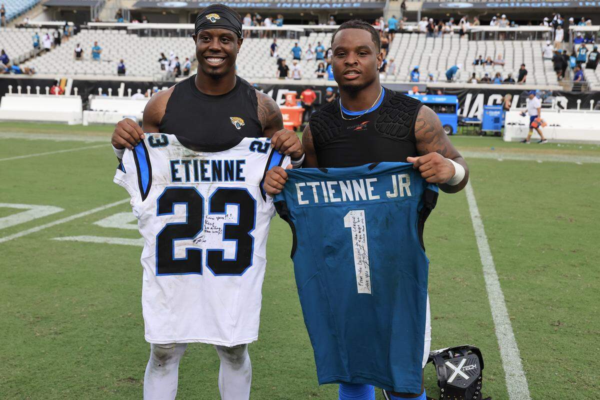 Travis Etienne Jr. (left), shown here as a member of the Jacksonville Jaguars, and Carolina Panthers running back Trevor Etienne (right) swap jerseys after the game at EverBank Stadium on September 07, 2025 in Jacksonville, Florida.