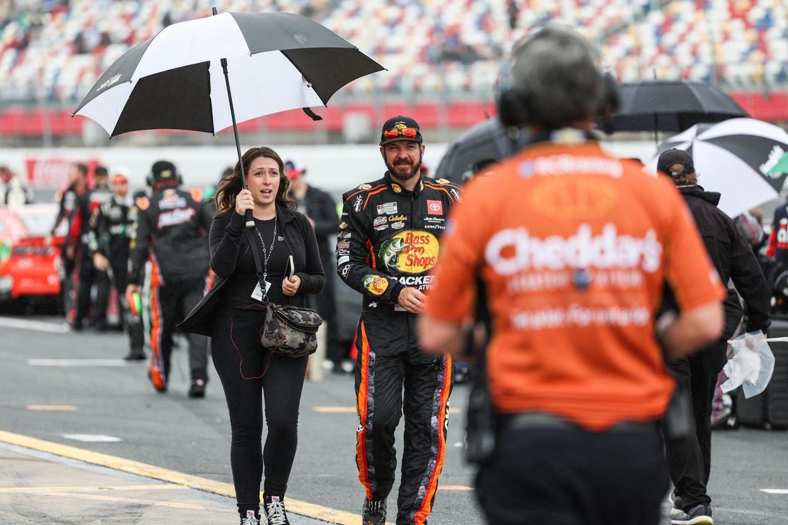 NASCAR Cup Series driver Martin Truex Jr. is escorted away from his car with an umbrella as a rain delay briefly stops the Coca-Cola 600 on Monday, May 29, 2023 at Charlotte Motor Speedway.
