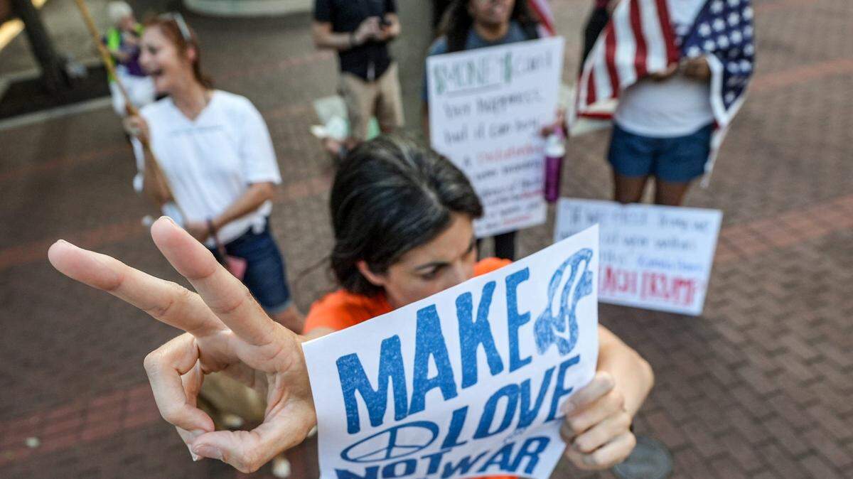 Sara Hamby of Simpsonville, S.C., flashes a peace sign shortly after President Donald Trump announced a cease fire between Iran and Israel. Hamby and others were standing along Main Street in Greenville, S.C., on Monday.