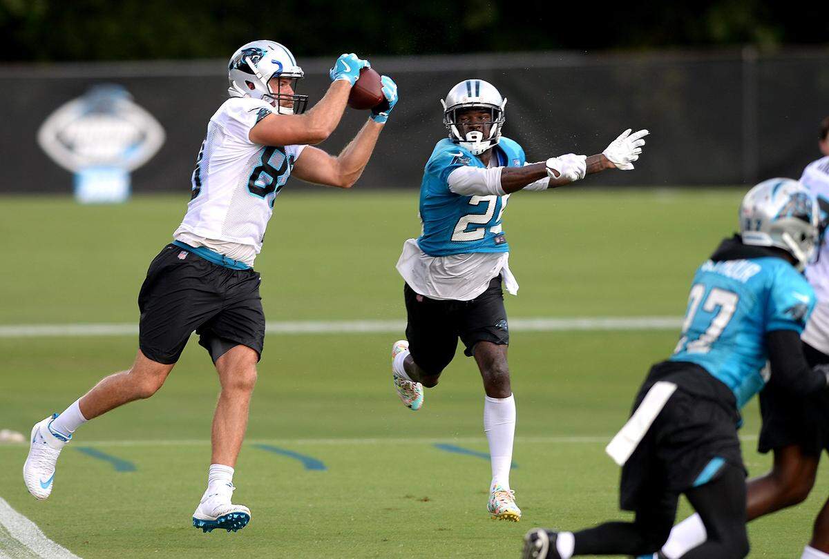 Carolina Panthers tight end Greg Olsen, left, catches a pass from quarterback Cam Newton as safety Damian Parms, right, applies defensive pressure during practice on Sunday, August 5, 2018 at Wofford College in Spartanburg, SC.