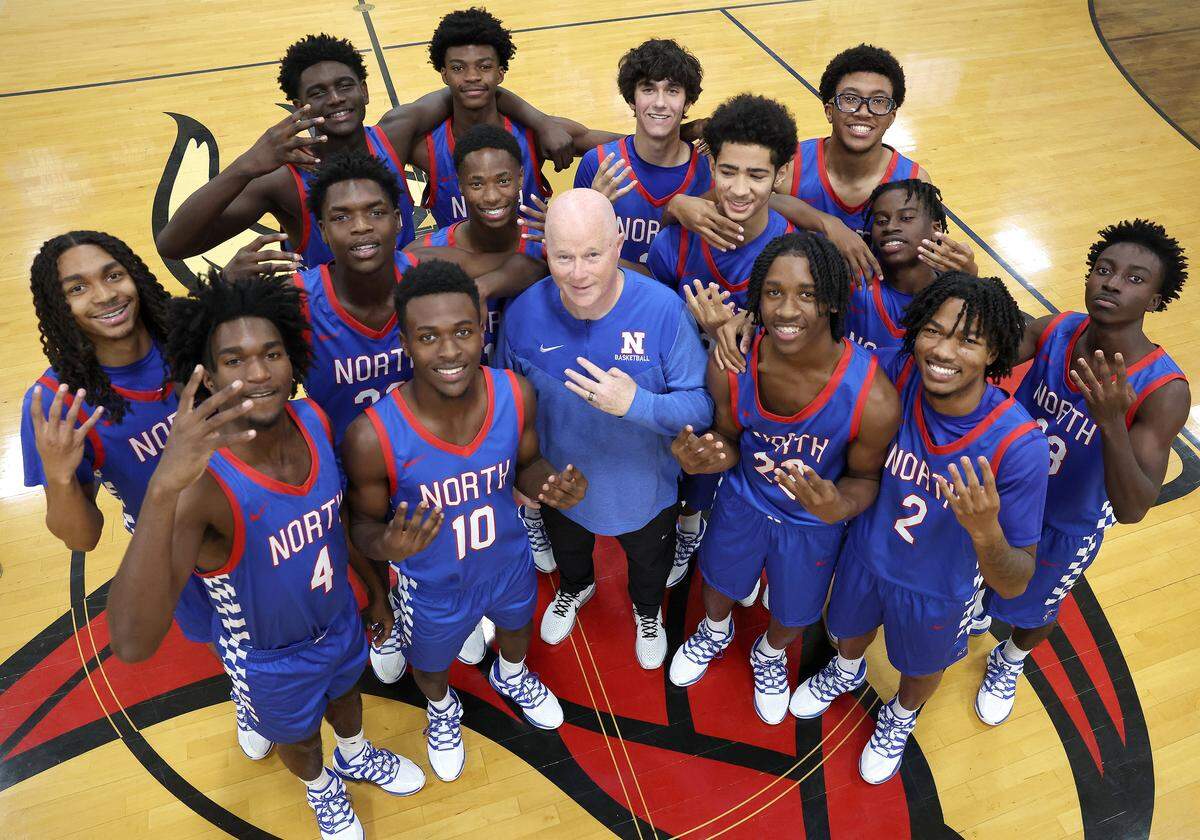 North Meck Vikings head basketball coach Duane Lewis, center and team members flash four fingers for the number of NCHSAA championships the school has won during Lewis' career at the school. The 2025 North Meck boys basketball team is ranked No.1 in the preseason sweet 16.