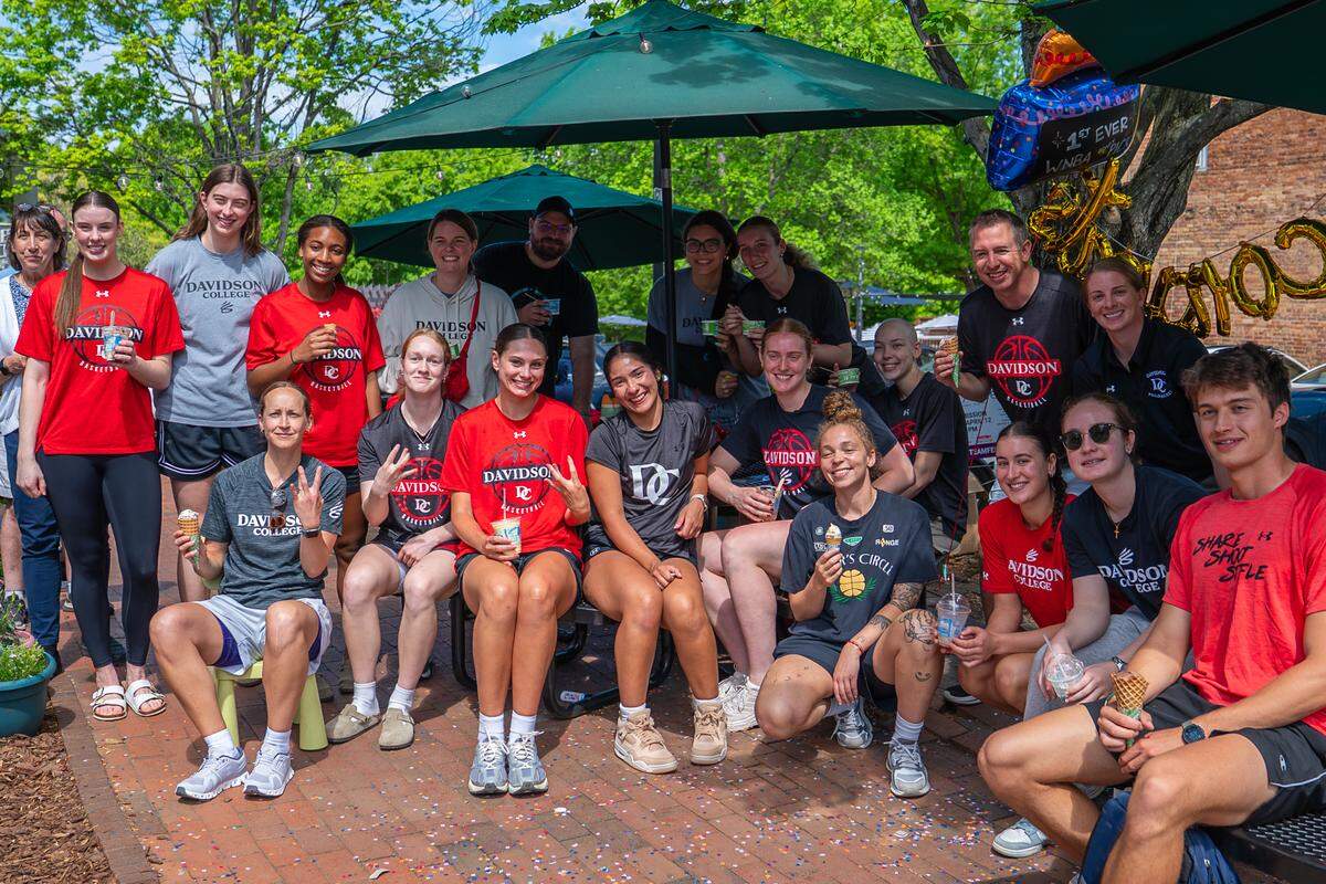 Davidson staff and players celebrate with women’s basketball senior Charlise Dunn (center) on April 14. On April 13, Dunn became the first WNBA draft pick in school history.