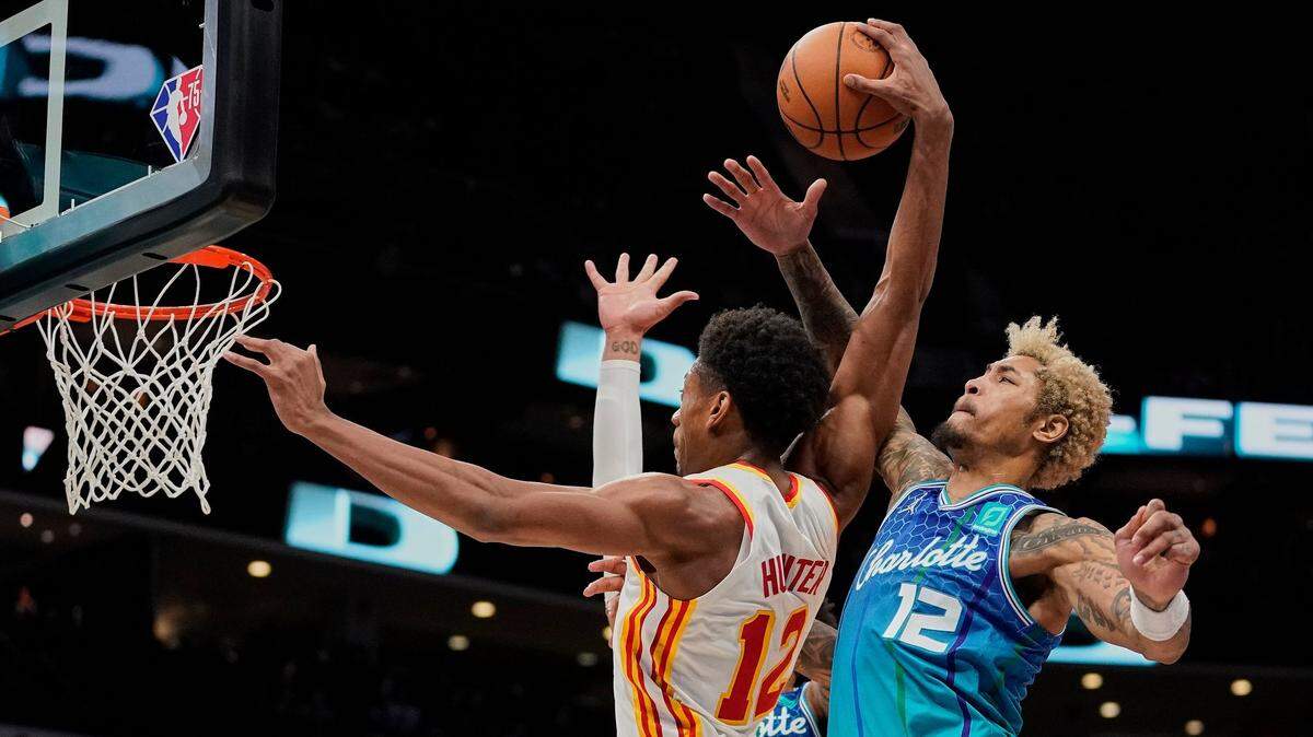 Atlanta Hawks forward De’Andre Hunter, left, drives to the basket as Charlotte Hornets guard Kelly Oubre Jr., right, attempts to block the shot during the second half of an NBA basketball game Sunday, Jan. 23, 2022, in Charlotte, N.C. Oubre was ejected from the game after review of the foul. (AP Photo/Rusty Jones)