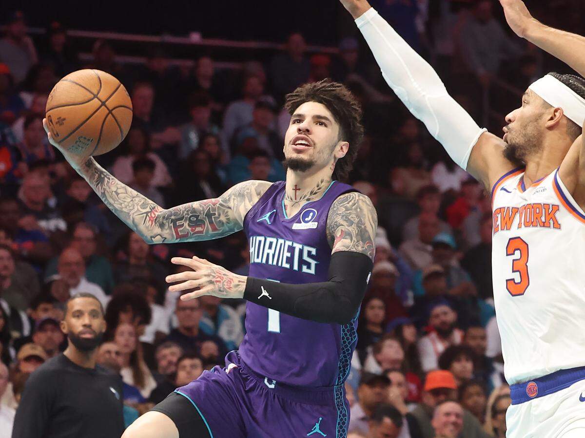 Charlotte Hornets guard LaMelo Ball, left, releases a one-handed runner as New York Knicks guard/forward Josh Hart applies defensive pressure during action at Spectrum Center in Charlotte, North Carolina, on Wednesday, Nov. 26, 2025.
