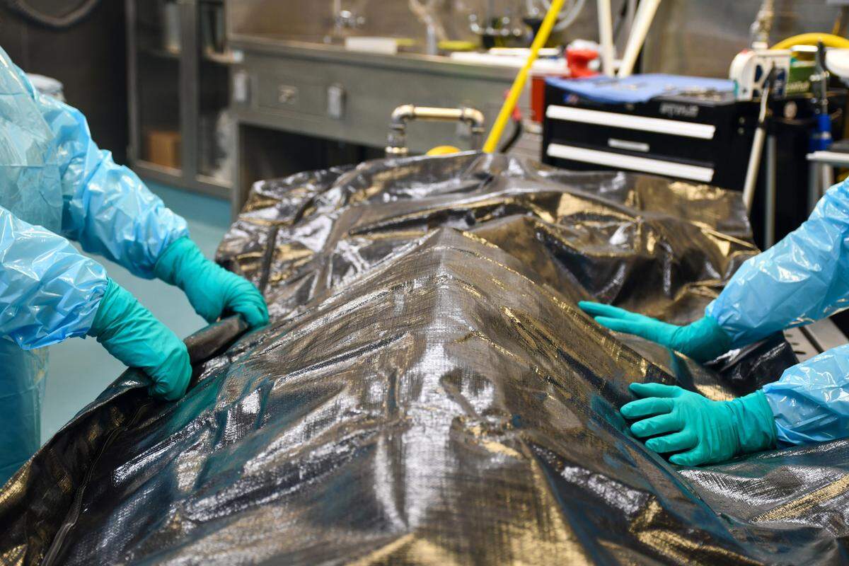 Two staff members at the chief medical examiner’s office in Raleigh prepare to transport a body. Medical examiner cases in North Carolina grew more than 30% over the past three years. A surge in drug overdose deaths is largely to blame.