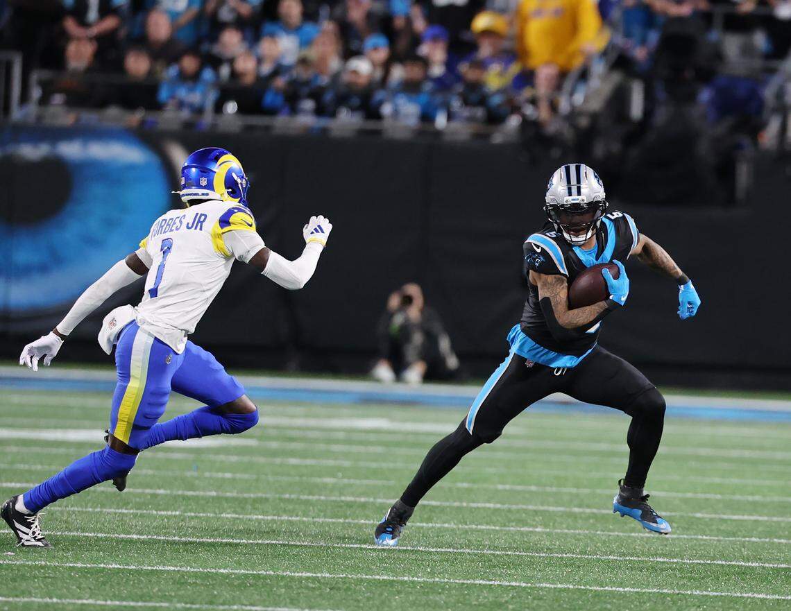 Carolina Panthers running back Rico Dowdle carries the ball against Los Angeles Rams corner back Emmanuel Forbes Jr. during a wild-card playoff game on Jan. 10, 2026, at Bank of America Stadium.