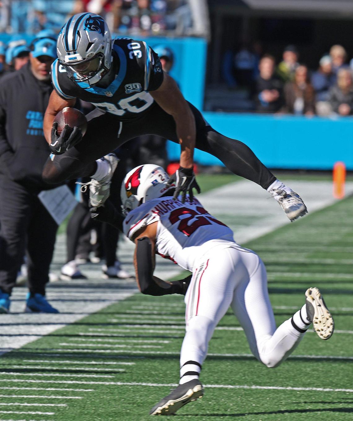 Carolina Panthers running back Chuba Hubbard leaps over Arizona Cardinals cornerback Sean Murphy-Bunting on a run during action at Bank of America Stadium in Charlotte, NC on Sunday, December 22, 2024.