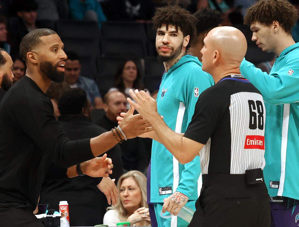 Charlotte Hornets guard LaMelo Ball, center, glances back at referee Jacyn Goble, right, and head coach Charles Lee, left, as they exchange greetings prior to action against the Indiana Pacers at Spectrum Center in Charlotte, N.C .on Thursday, Jan. 8, 2026. Ball did not start the game.