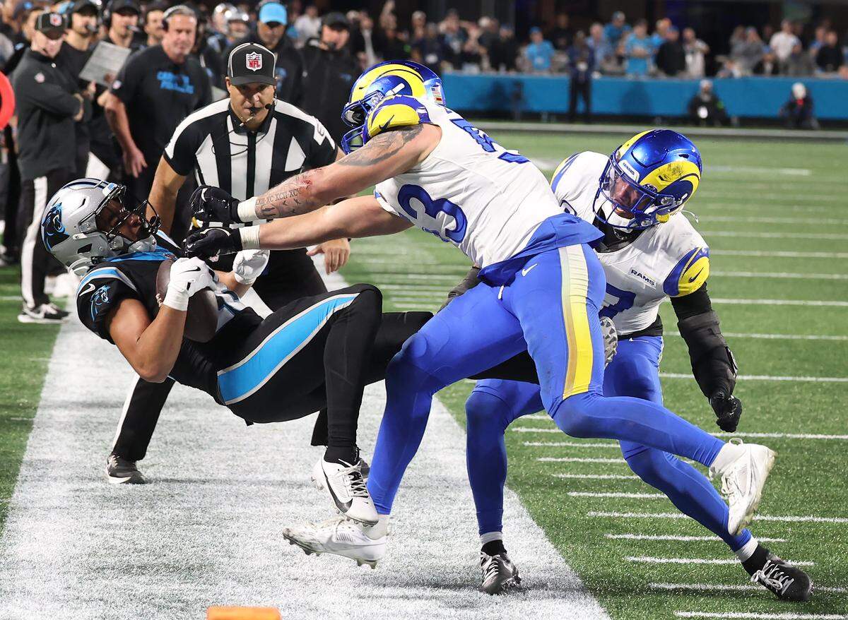 Carolina Panthers wide receiver Jalen Coker, left, is pushed out of bounds by Los Angeles Rams linebacker Nate Landman, center, following a pass reception on Jan. 10, 2026, at Bank of America Stadium. Landman was penalized on the play. The Rams defeated the Panthers 34-31.