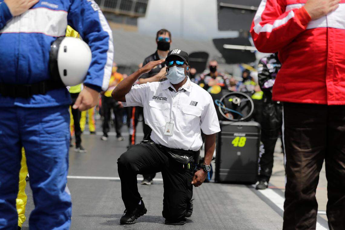 A NASCAR official kneels during the national anthem before a NASCAR Cup Series auto race at Atlanta Motor Speedway on Sunday, June 7, 2020, in Hampton, Ga. NASCAR paused before Sunday’s Cup race at Atlanta Motor Speedway to acknowledge the country’s social unrest. (AP Photo/Brynn Anderson)