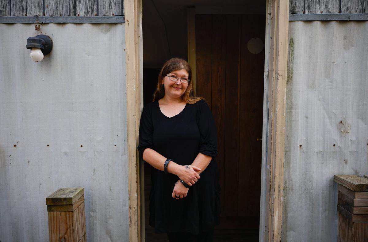 April Woody stands in the doorweay to her home in Spruce Pine, NC on Monday, November 18, 2024. Woody sustained power and water outage and fell behind on utility bills. Her family was adopted by a family in Illinois who will be helping fulfill the family’s Christmas wishlist, as well as having provided some money to an outstanding bill.