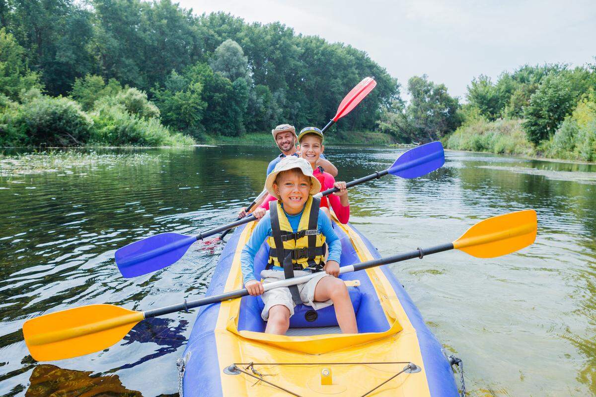 A family smiling in a kayak on a river.