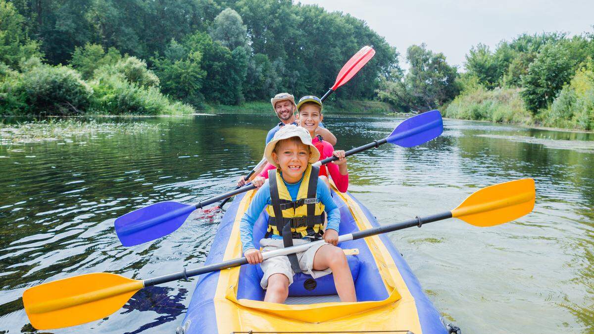 A family smiling in a kayak on a river.