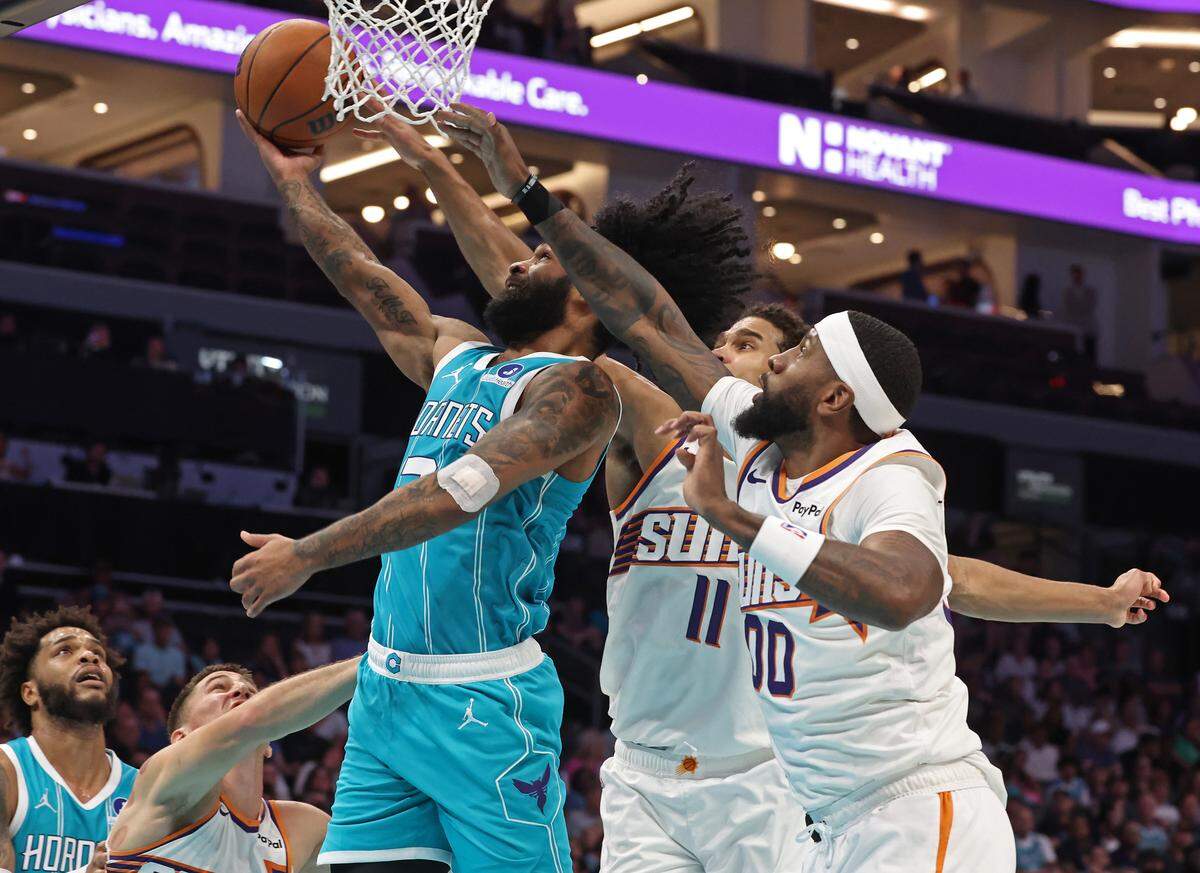 Charlotte Hornets guard Coby White, left, drives to the basket past Phoenix Suns center Oso Ighodaro, center and forward Royce O’Neale during action at Spectrum Center in Charlotte, North Carolina, on Thursday, April 2, 2026.