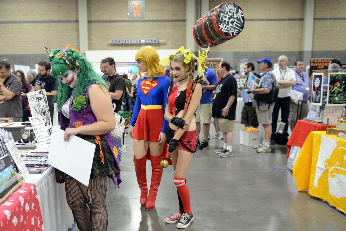 Brianne Dameron, dressed as the Joker, Natalie Belcher, as Supergirl, and PJ Clark, as Harley Quinn, walk through HeroesCon to look at comic books in June 2017 in the Charlotte Convention Center.