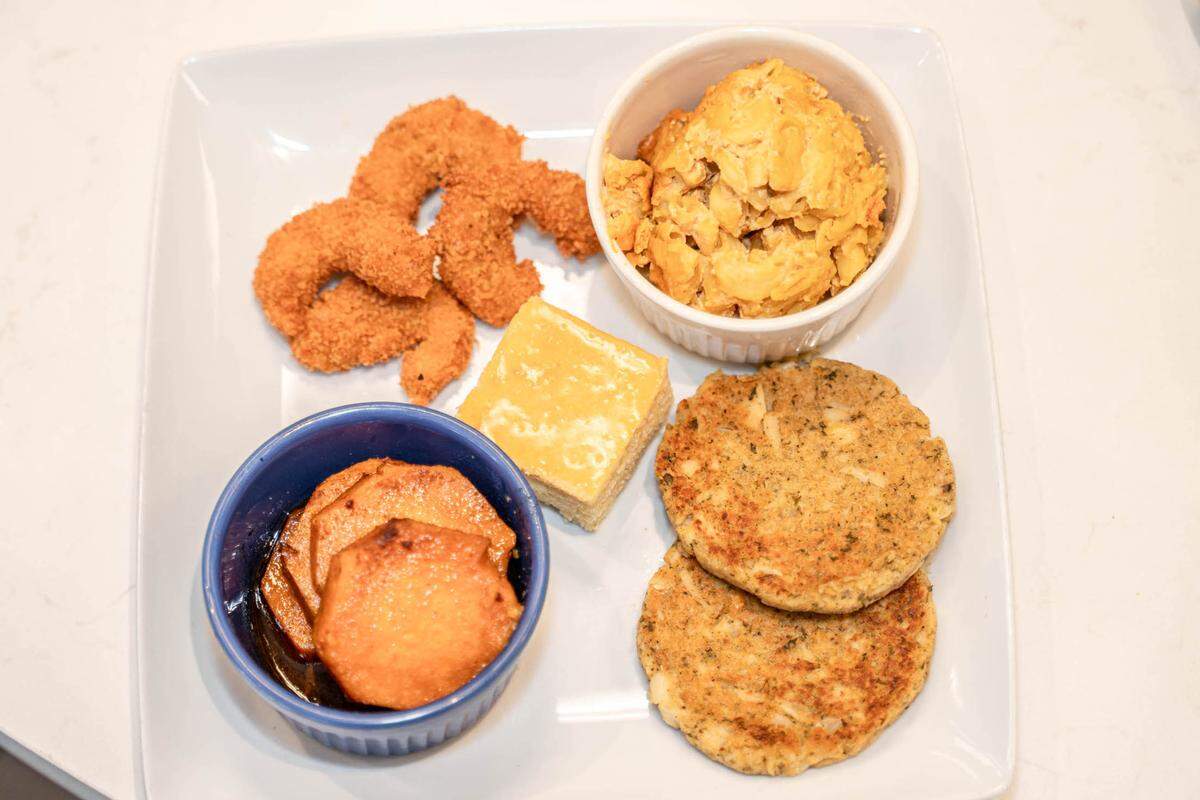 A VelTree Soul Plate with fried shrimp, yams, crab cake patties, cornbread, and mac and cheese.
