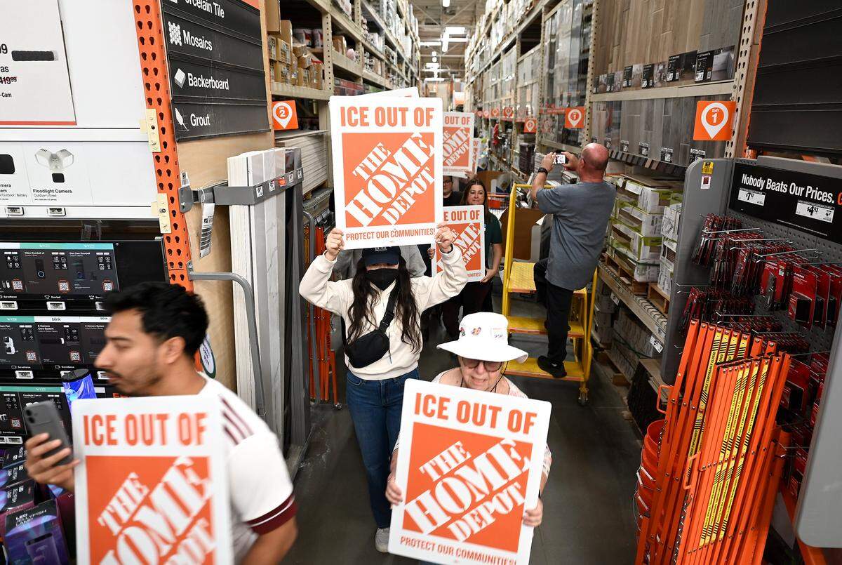 Protesters walk down an aisle at the Home Depot on North Wendover Road in Charlotte on Wednesday, November 19, 2025. 