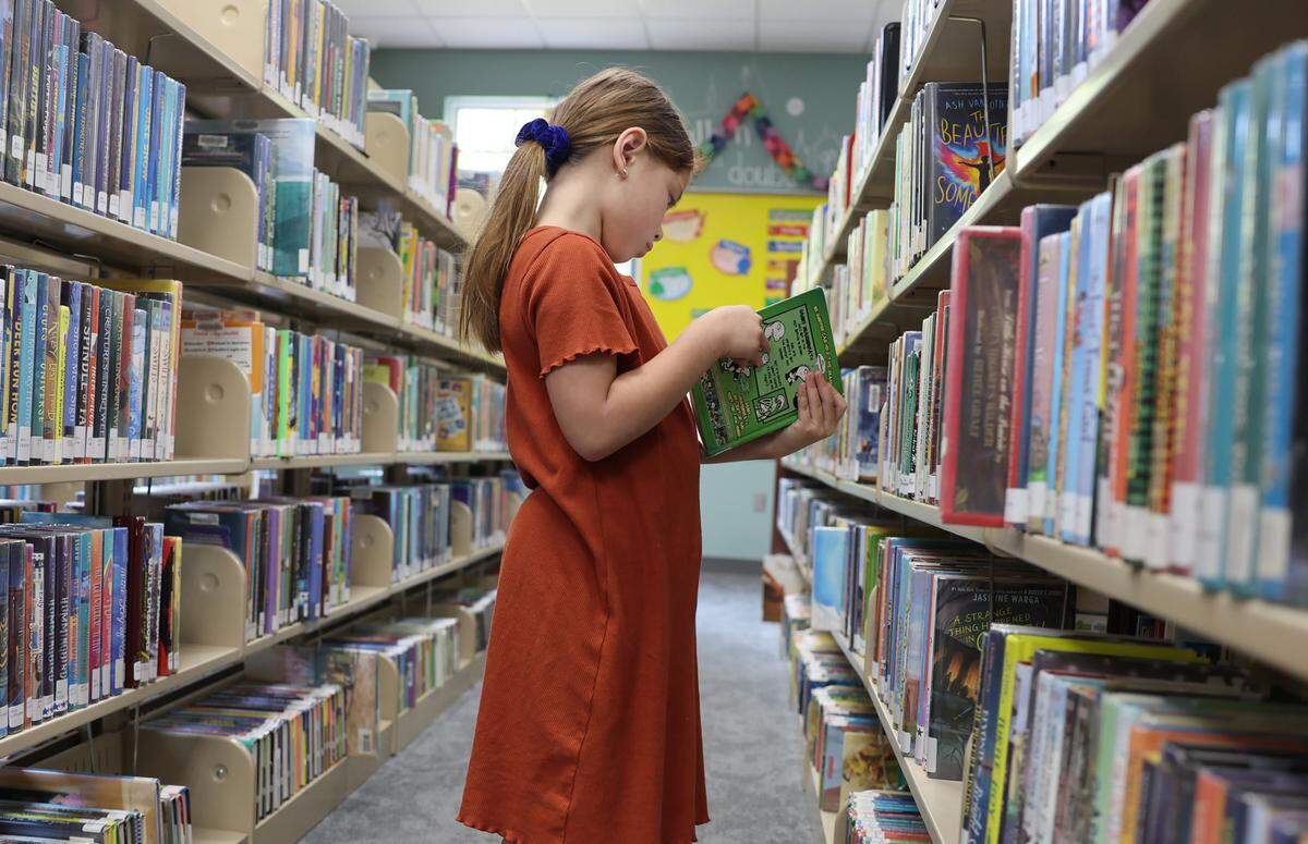 7-year-old Madilyn Hardgrove looks at a book on Friday, May 9, 2025, at the Fort Mill Library, SC. South Carolina leads the nation in public school book bans, with over half linked to one parent’s challenges in Beaufort County, sparking statewide debate on censorship and educational content.