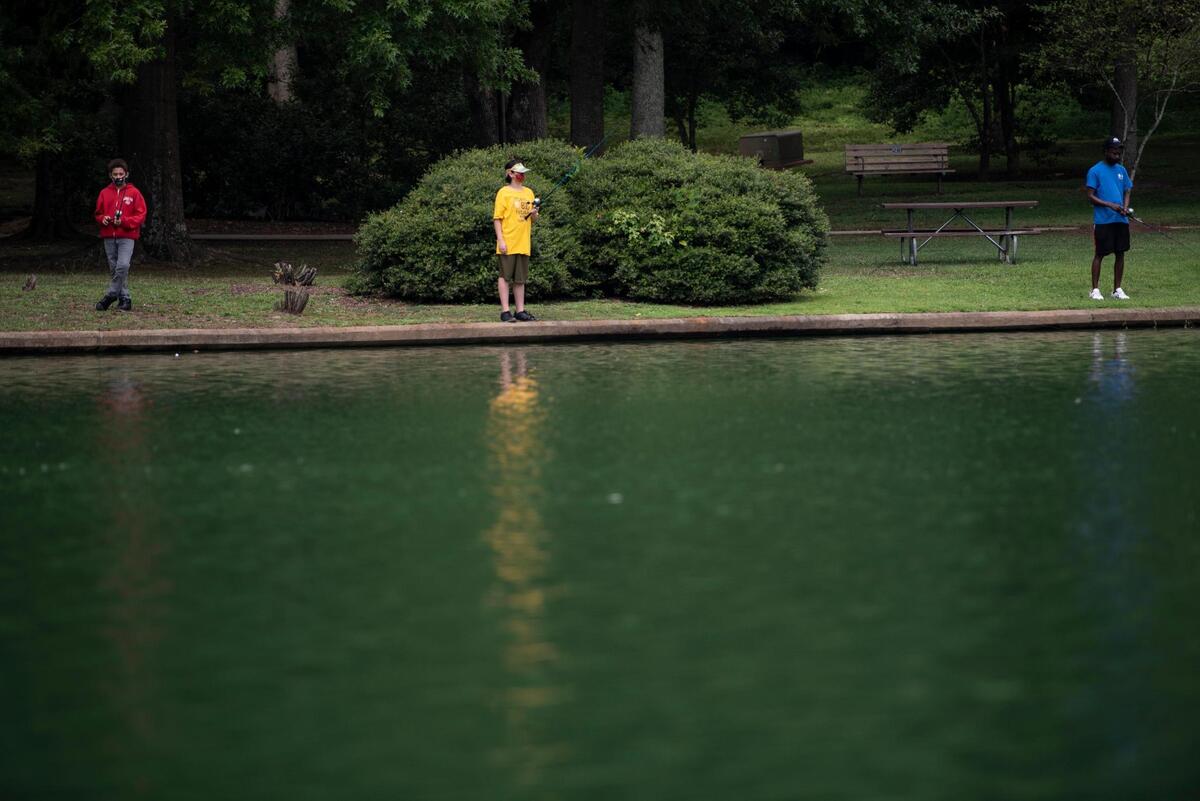 People fish in the waters where a toxic blue-green algae has appeared at Freedom Park in Charlotte, N.C., on Wednesday, July 29, 2020.
