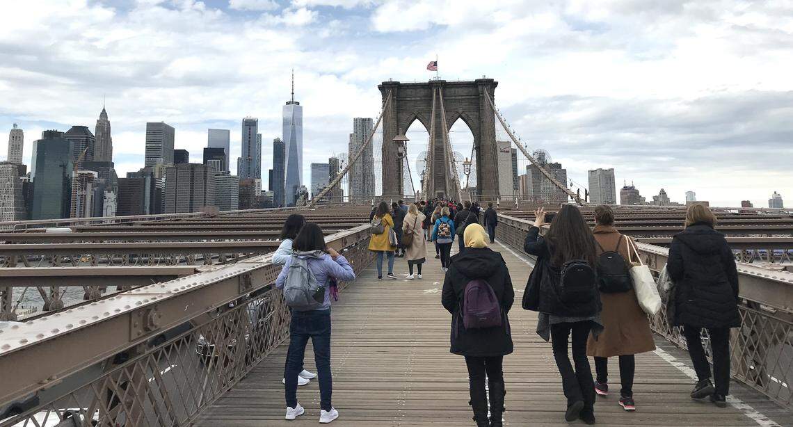 Tourists on the Brooklyn Bridge check out the Manhattan skylines in this 2018 photo. In March 2020, flights from Charlotte to Newark, New Jersey, were lower than usual on American Airlines. Travelers heading to New York City often fly through Newark.