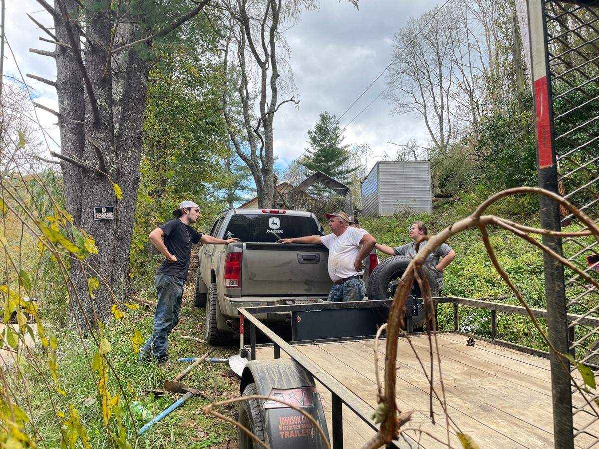 Logan Brown, 17, left, and his father, right, deliberate where to put the dirt bikes they just recovered from their home on Thursday, Oct. 3, 2024, after Hurricane Helene covered everything with mud.