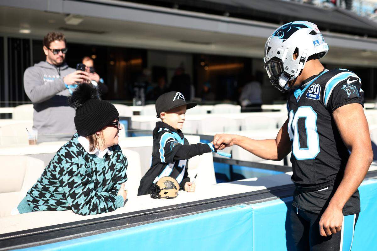 Chuba Hubbard of the Carolina Panthers fist-bumps a young fan prior to a 2024 game against the Arizona Cardinals at Bank of America Stadium.