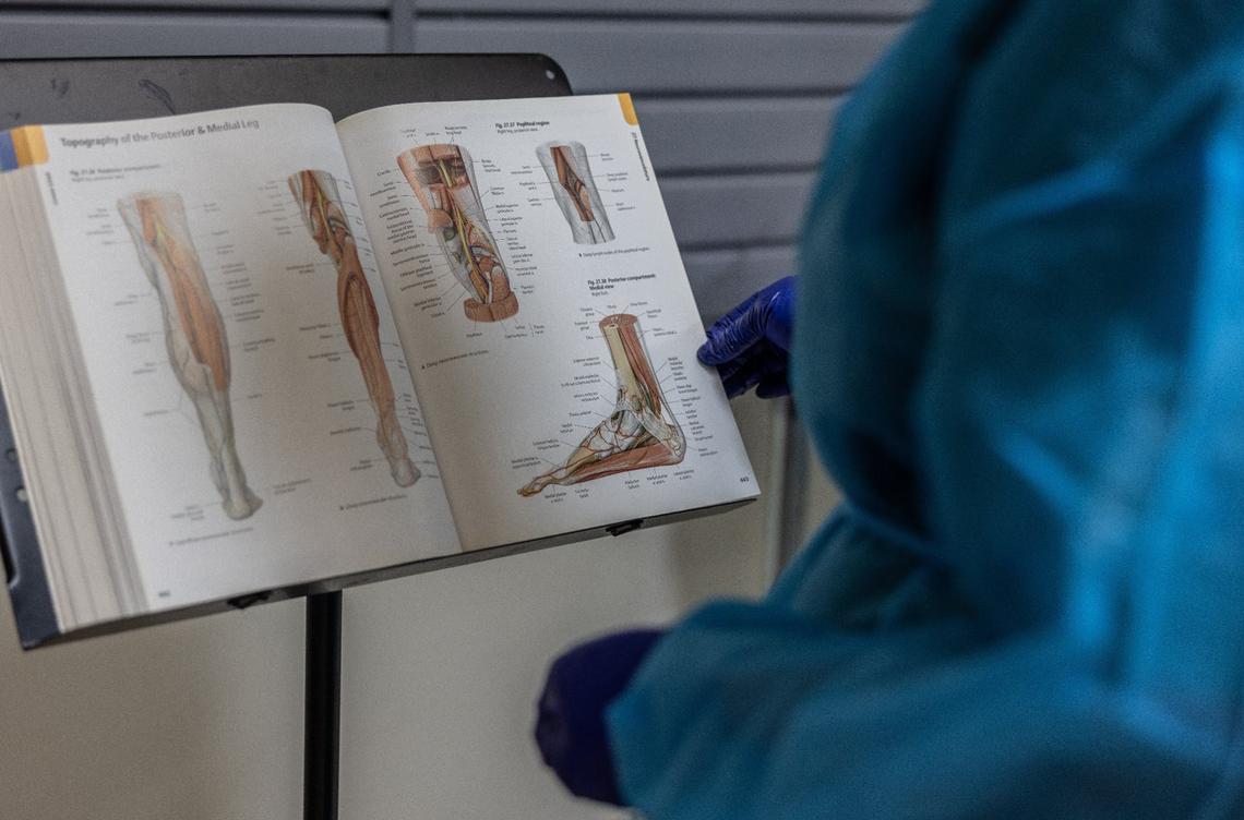 Katie Hopkins refers to an anatomy book during a workshop at Experience Anatomy in Charlotte.