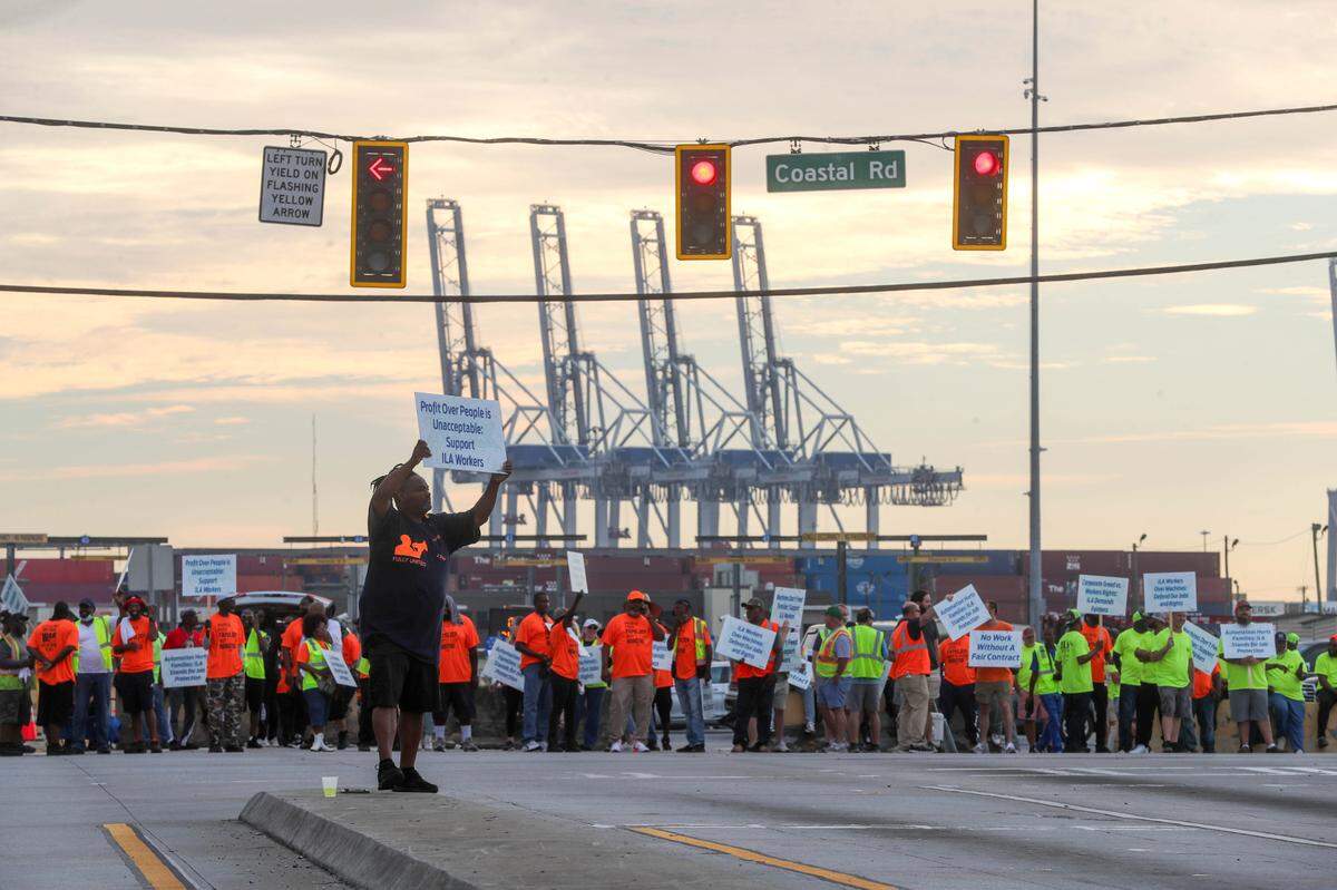 An International Longshoremen’s Association member holds a picket sign along with fellow union members outside the entrance to the Garden City Terminal in Georgia on Tuesday as the ILA went on strike at the Georgia Ports Authority. The Carolinas face supply chain concerns on staple items as a port strike follows damage from Hurricane Helene.