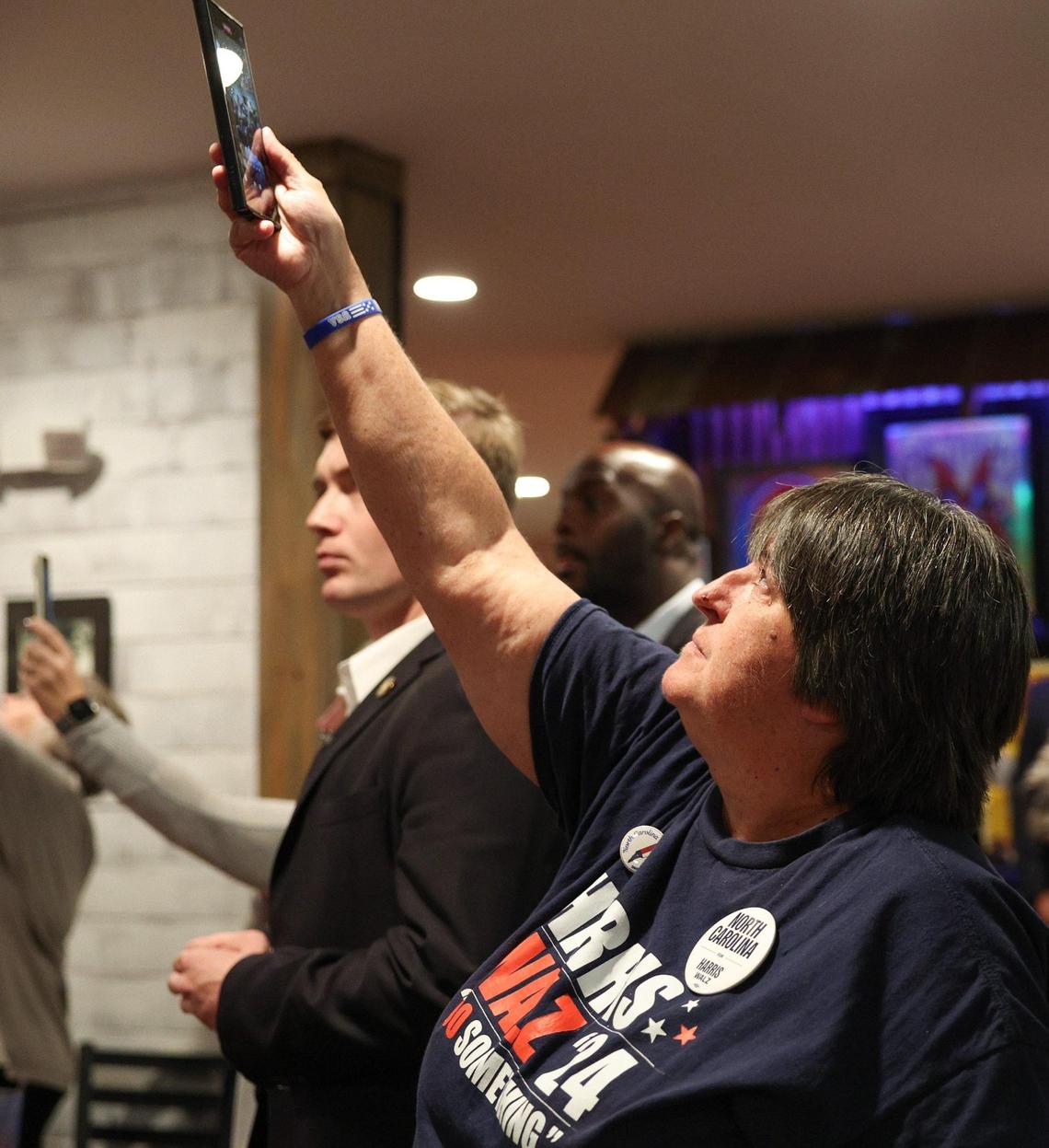 A supporter uses her cell phone to document Gov. Tim Walz as he hosts an event on behalf of the Harris-Walz ticket at RayNathan’s Sunday.
