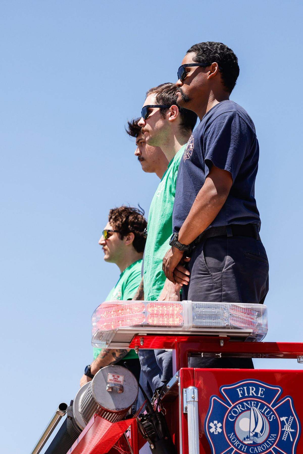 Members of the Cornelius Fire Department stand on top of a truck as the law enforcement processional for Deputy U.S. Marshal Thomas “Tommy” Weeks Jr. goes along Interstate 77 at exit 28 on Wednesday, May 1, 2024. Weeks, a 48-year Mooresville father of four, died in Monday’s Charlotte shooting where four law enforcement officers died and four more wounded.